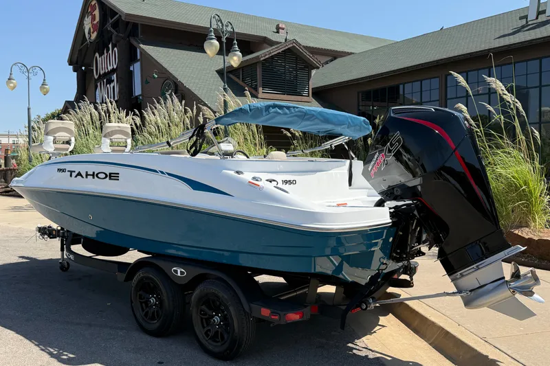 Slide: The Image of 2027 Tahoe 1950 boat with outboard motor, parked outside a store. - 4
