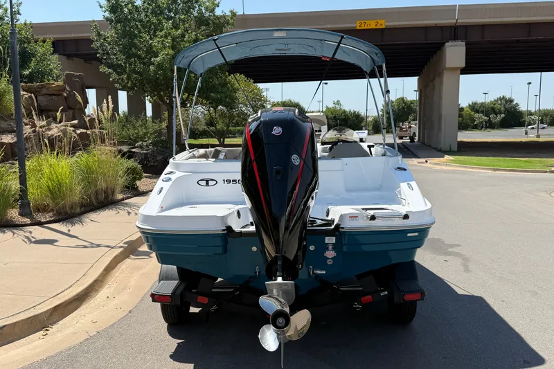 Slide: The Image of 2027 Tahoe 1950 boat with outboard motor, parked under a bridge on a sunny day. - 19