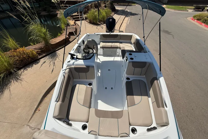 Slide: The Image of 2027 Tahoe 1950 boat with spacious seating and canopy, parked near a pond. - 7
