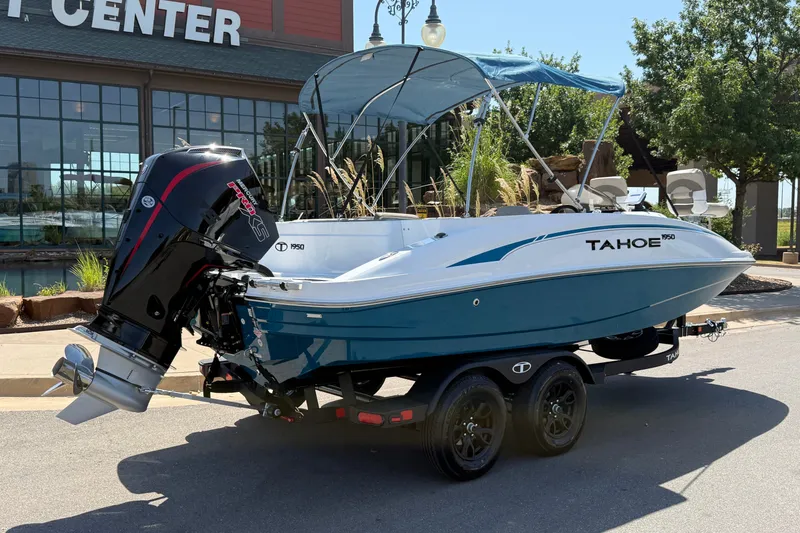 Slide: The Image of 2027 Tahoe 1950 boat with outboard motor on trailer, parked outside a center. - 18