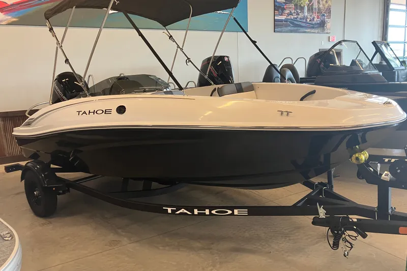 The Image of 2027 Tahoe T16 boat on trailer in showroom, featuring sleek design and canopy. - 0