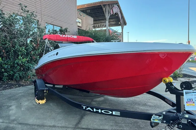 Slide: The Image of 2027 Tahoe T18 boat with red hull on trailer, parked outdoors. - 2