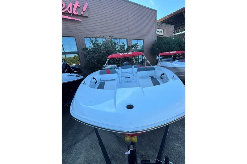 Slide: The Image of 2027 Tahoe T18 boat with red canopy, displayed outdoors at a dealership. - 1