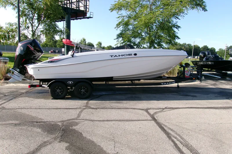 The Image of 2027 Tahoe T21 boat on trailer, parked outdoors, with trees in the background. - 0