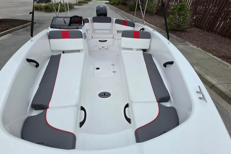 Slide: The Image of 2027 Tahoe T18 boat interior with gray and red seating, parked outdoors. - 11