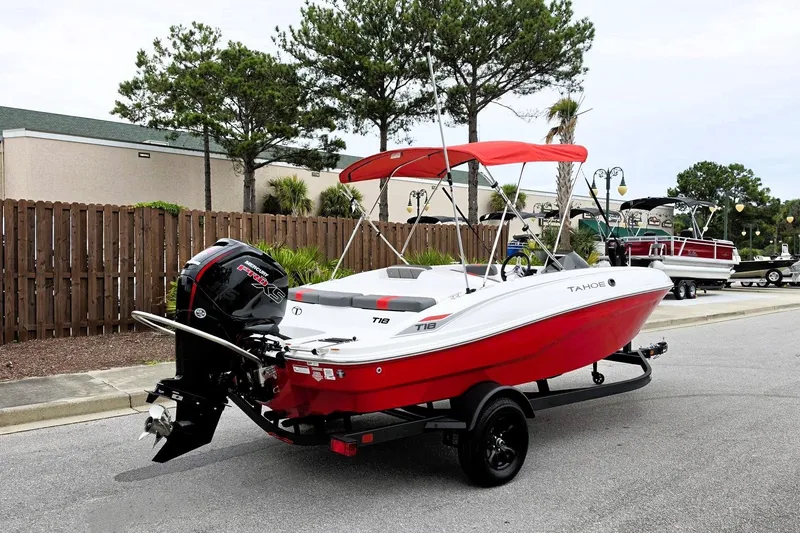 Slide: The Image of 2027 Tahoe T18 boat with red hull and canopy on a trailer. - 2