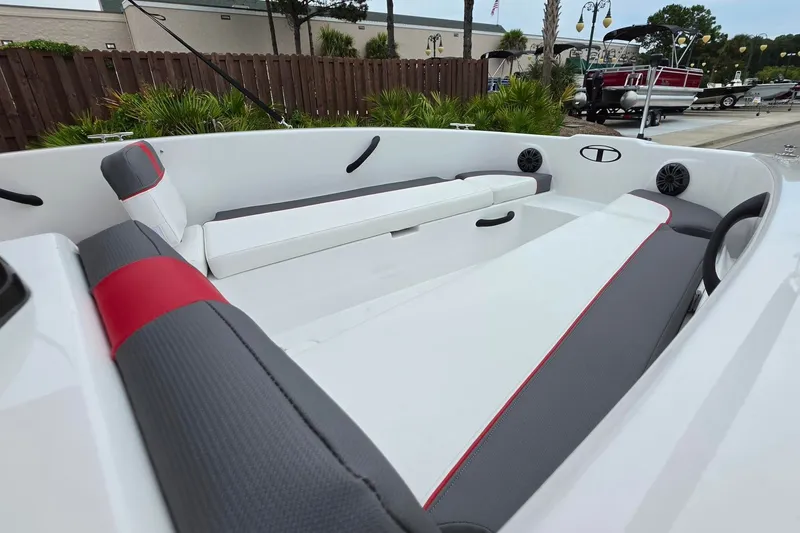 Slide: The Image of 2027 Tahoe T18 boat interior with gray and red seating, docked outdoors. - 14