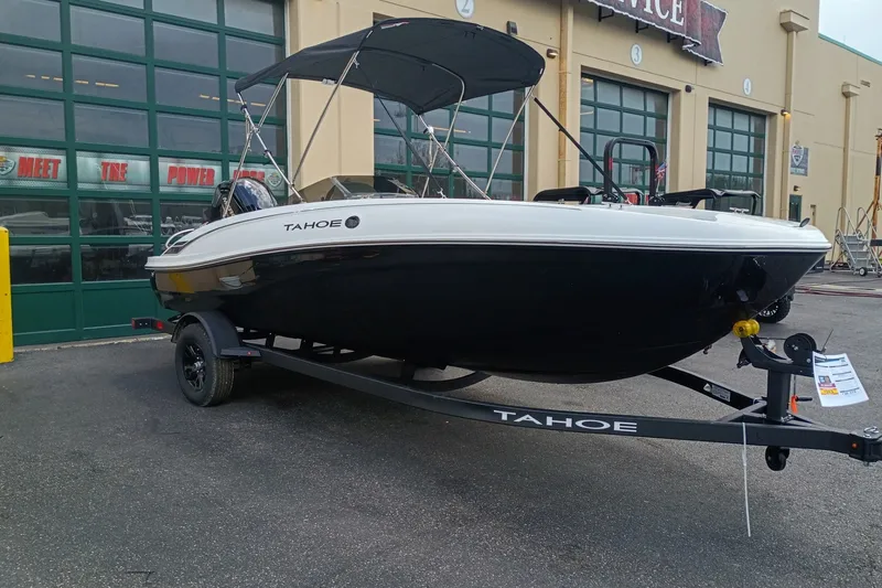 The Image of 2027 Tahoe T18 boat on trailer outside a garage with green doors. - 0