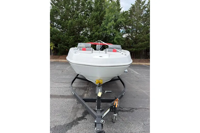 Slide: The Image of 2027 Tahoe T21 boat on trailer, parked on asphalt with trees in background. - 7