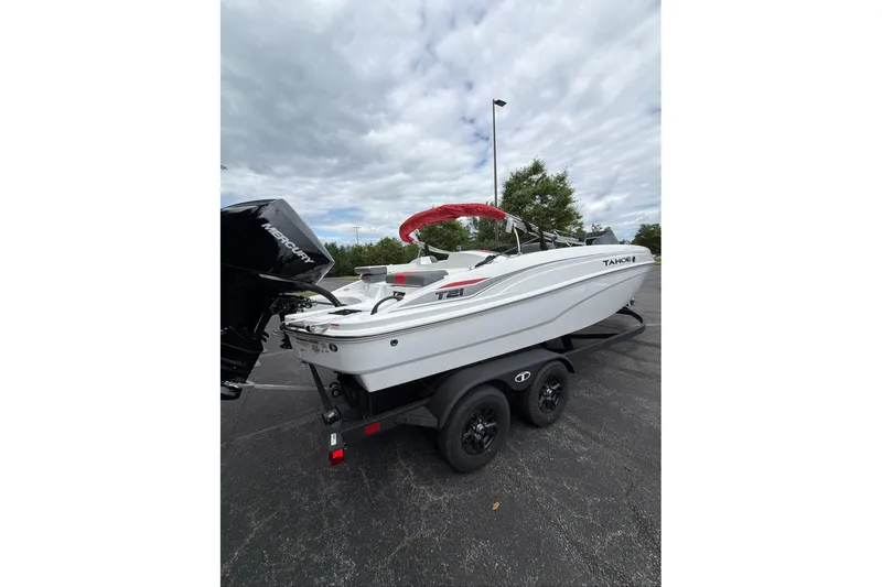 Slide: The Image of 2027 Tahoe T21 boat on trailer with Mercury engine, parked outdoors under cloudy sky. - 5