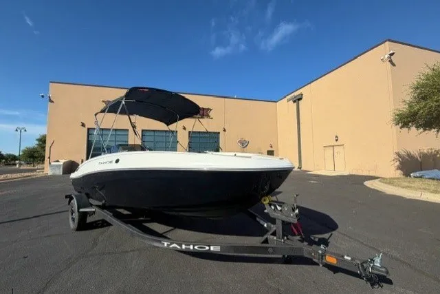 The Image of 2027 Tahoe T18 boat on trailer, parked outside a beige building under clear blue sky. - 0