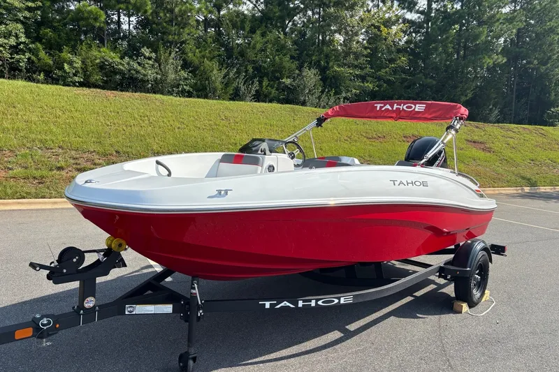 Slide: The Image of Red and white 2027 Tahoe T16 boat on trailer, parked outdoors. - 2