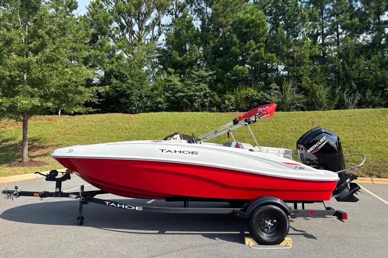 The Image of Red and white 2027 Tahoe T16 boat on trailer, parked outdoors. - 0