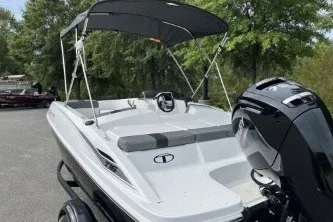 Slide: The Image of 2027 Tahoe T16 boat with canopy and outboard motor, parked outdoors. - 7