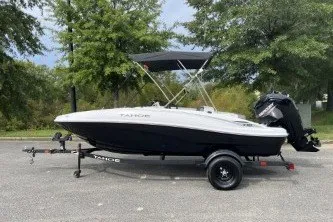 The Image of 2027 Tahoe T16 boat on trailer, parked outdoors with trees in background. - 0