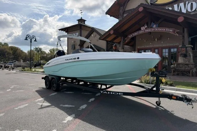 The Image of 2027 Tahoe T21 boat on trailer outside outdoor store, under cloudy sky. - 0