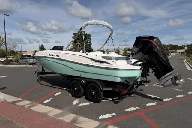 Slide: The Image of 2027 Tahoe T21 boat on trailer in parking lot under cloudy sky. - 2