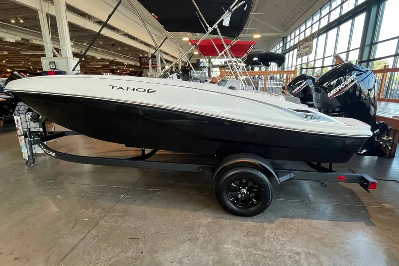 The Image of 2027 Tahoe T18 boat on trailer in showroom, featuring sleek design and Mercury outboard engine. - 0