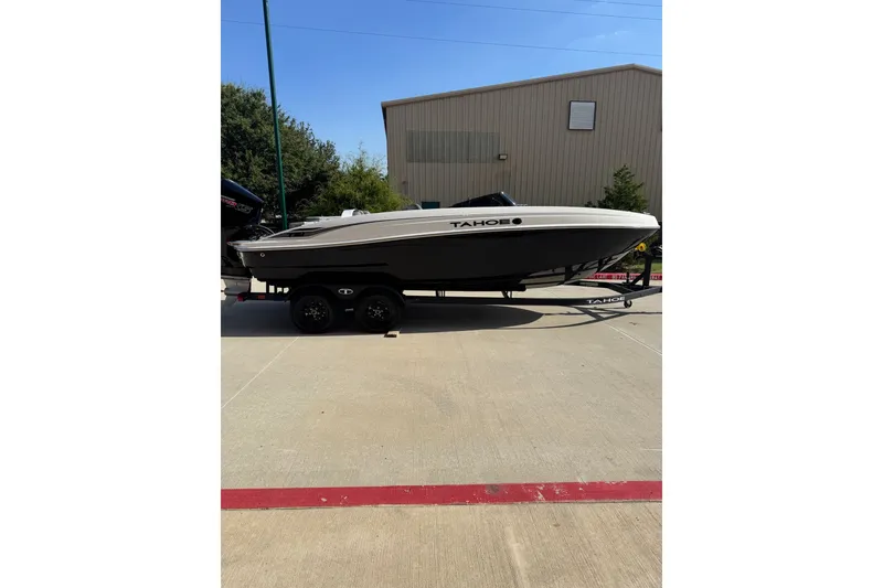 The Image of 2027 Tahoe T21 boat on trailer, parked outdoors near a building. - 0