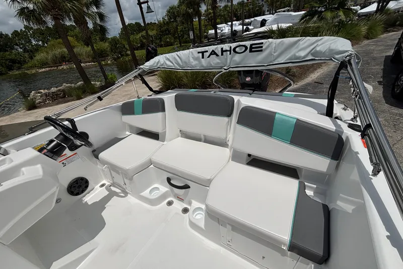 Slide: The Image of 2027 Tahoe T18 boat interior with white and gray seating, docked near lush greenery. - 11