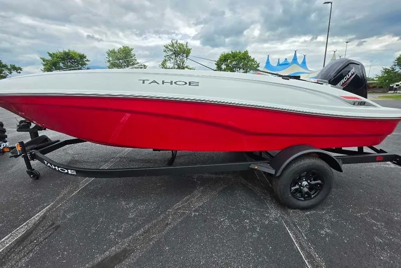 The Image of 2027 Tahoe T18 boat with red hull on trailer, parked outdoors under cloudy sky. - 0