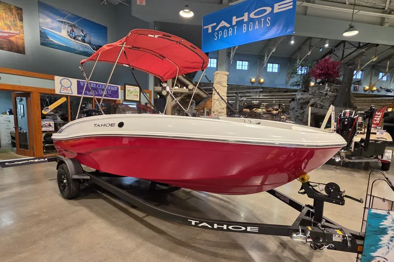 Slide: The Image of 2027 Tahoe T18 boat with red hull and canopy on display indoors. - 1
