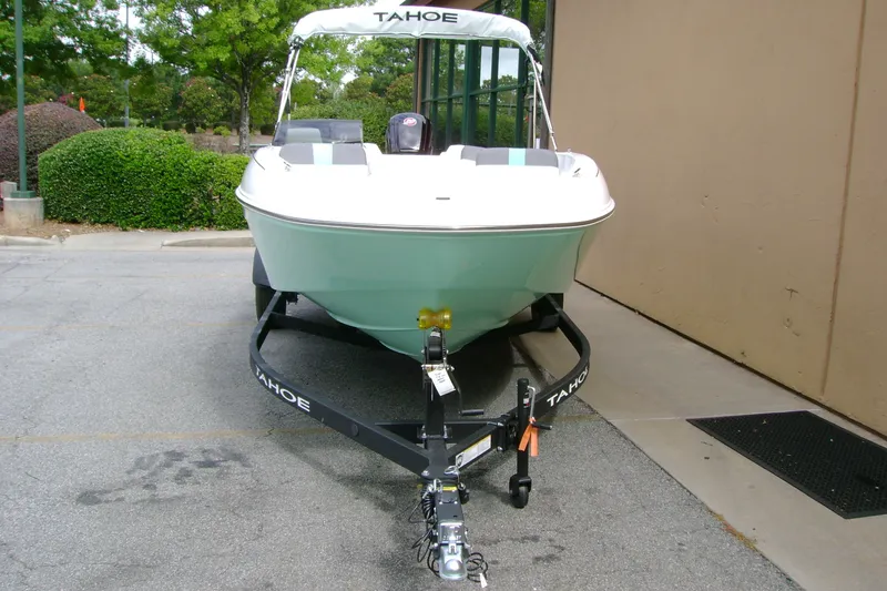 Slide: The Image of 2027 Tahoe T18 boat on trailer, parked outdoors near greenery and building. - 6