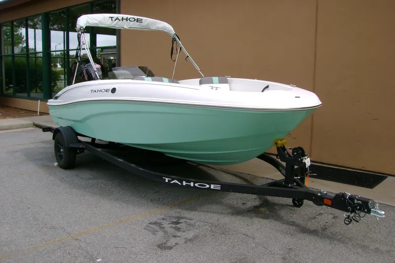 Slide: The Image of 2027 Tahoe T18 boat on trailer, parked outdoors, mint green hull. - 2