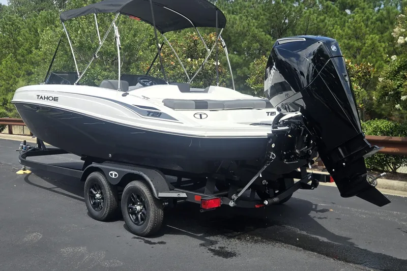 Slide: The Image of 2027 Tahoe T21 boat on trailer, parked outdoors with trees in background. - 1