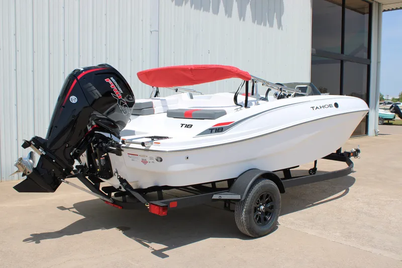Slide: The Image of 2027 Tahoe T18 boat with red canopy on trailer, parked outside a building. - 4