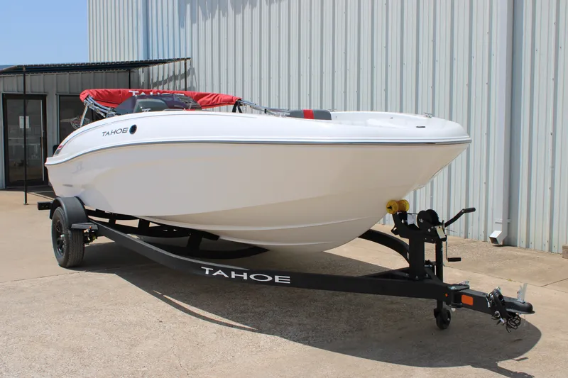 Slide: The Image of 2027 Tahoe T18 boat on trailer, parked outdoors near a metal building. - 1