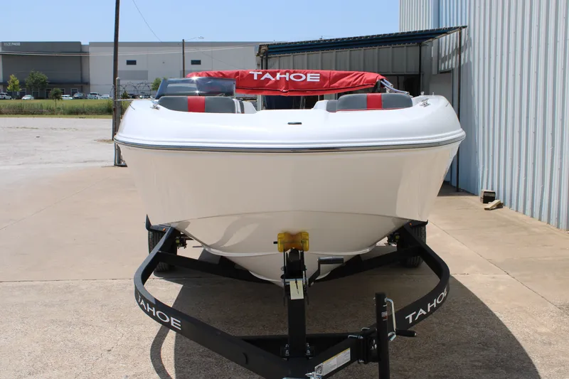 Slide: The Image of 2027 Tahoe T18 boat on trailer, parked outdoors near industrial building. - 2