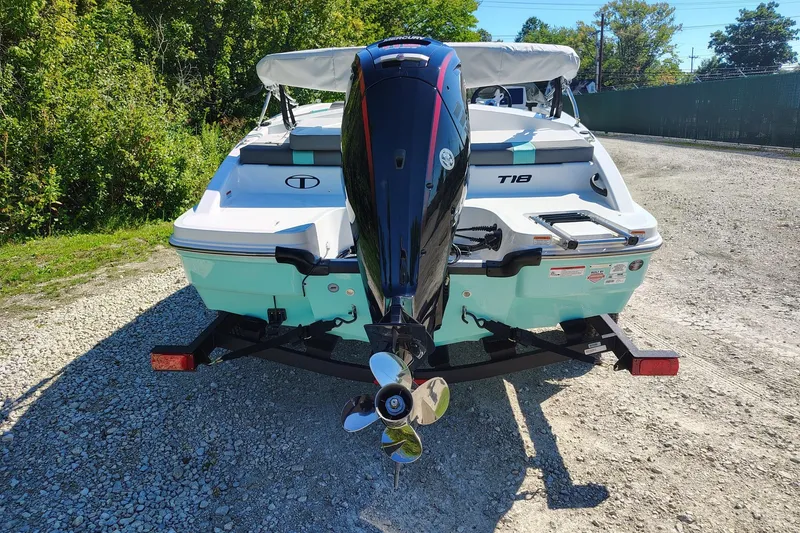 Slide: The Image of 2027 Tahoe T18 boat with outboard motor on a gravel path, surrounded by greenery. - 2