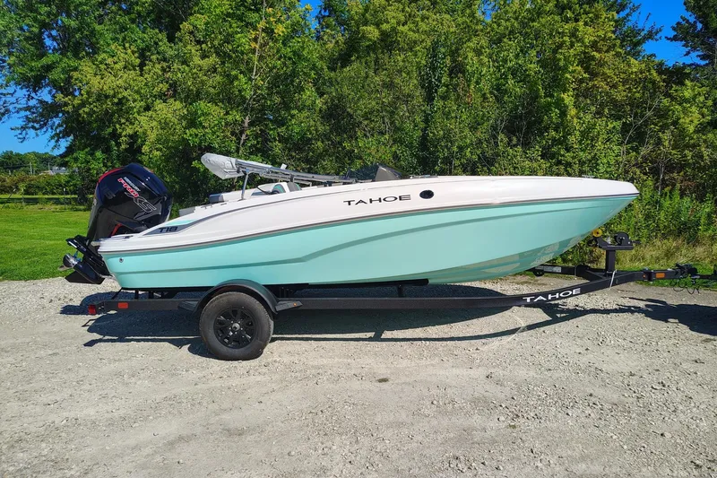 The Image of 2027 Tahoe T18 boat on trailer, parked outdoors with lush green background. - 0