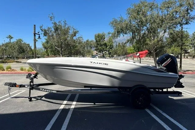 Slide: The Image of 2027 Tahoe T18 boat on trailer in parking lot, surrounded by trees. - 1