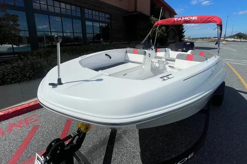Slide: The Image of 2027 Tahoe T18 boat with red canopy, parked outdoors on a sunny day. - 2
