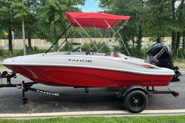 Slide: The Image of 2027 Tahoe T16 boat with red canopy on trailer, parked outdoors. - 1