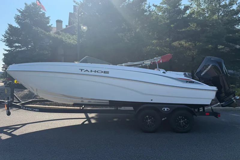 The Image of 2027 Tahoe T21 boat on trailer, parked outdoors with trees in background. - 0