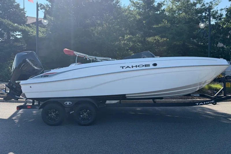Slide: The Image of 2027 Tahoe T21 boat on trailer, parked outdoors, with trees in the background. - 1