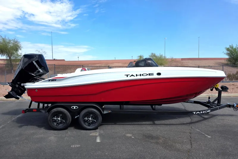 The Image of 2027 Tahoe T21 boat with red hull on trailer, parked outdoors under blue sky. - 0
