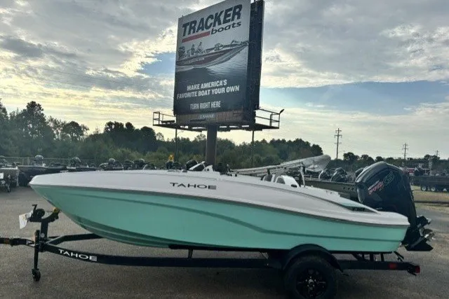 The Image of 2027 Tahoe T18 boat on trailer, parked near Tracker Boats billboard under cloudy sky. - 0