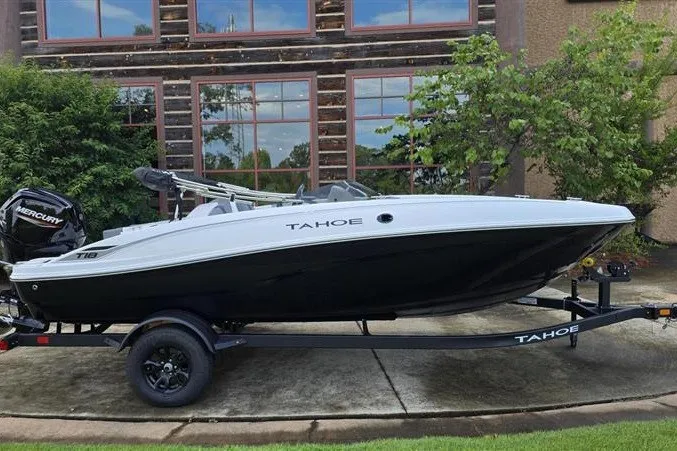 Slide: The Image of 2027 Tahoe T18 boat on trailer, parked outdoors near a building with large windows. - 4