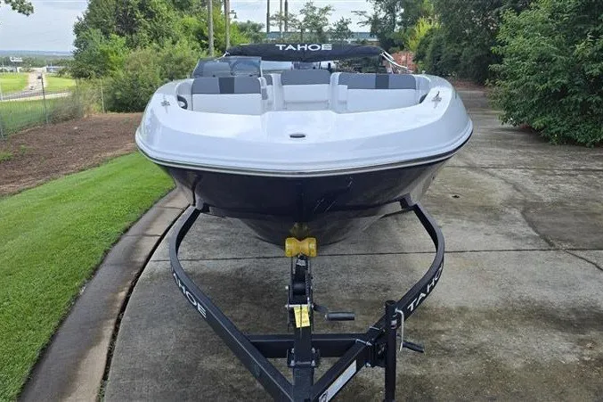 Slide: The Image of 2027 Tahoe T18 boat on trailer, parked on a driveway surrounded by greenery. - 6