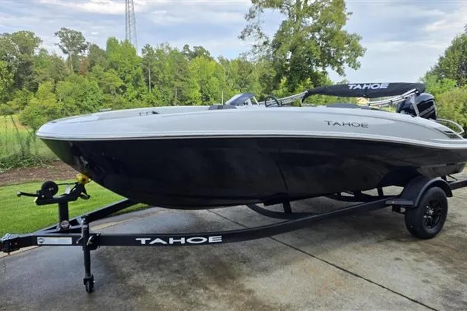 Slide: The Image of 2027 Tahoe T18 boat on trailer, parked outdoors with lush greenery in the background. - 7