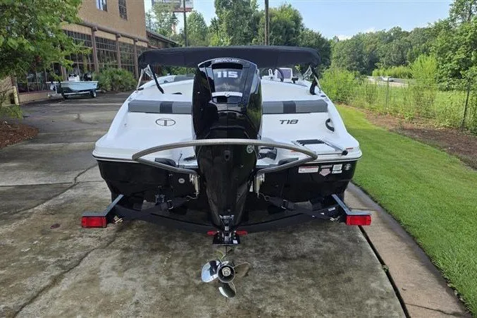 Slide: The Image of 2027 Tahoe T18 boat with outboard motor on a trailer, parked outdoors. - 2