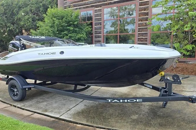 Slide: The Image of 2027 Tahoe T18 boat on trailer, parked outdoors near a wooden building. - 5
