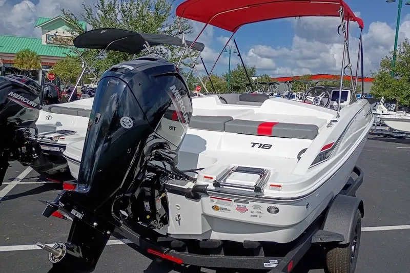 Slide: The Image of 2027 Tahoe T18 boat with Mercury engine, red canopy, parked outdoors under blue sky. - 2