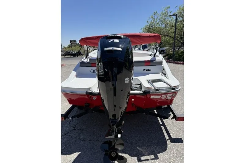 Slide: The Image of 2027 Tahoe T16 boat with Mercury 75 engine, red and white design, parked outdoors. - 2