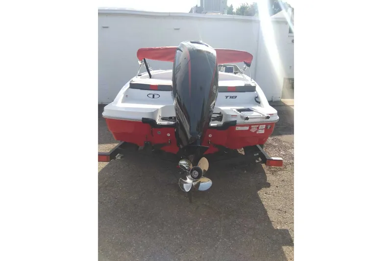 Slide: The Image of 2027 Tahoe T18 boat with outboard motor, red and white design, parked on trailer. - 2