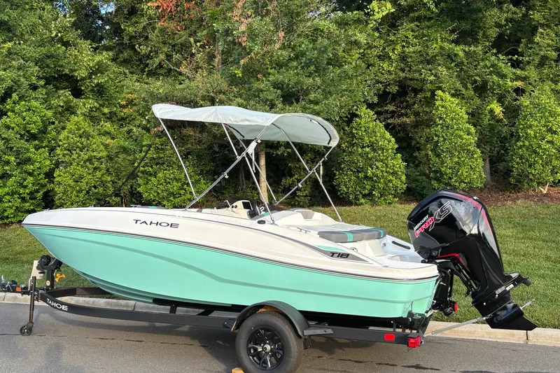 Slide: The Image of 2027 Tahoe T18 boat with canopy and outboard motor on trailer, surrounded by greenery. - 3